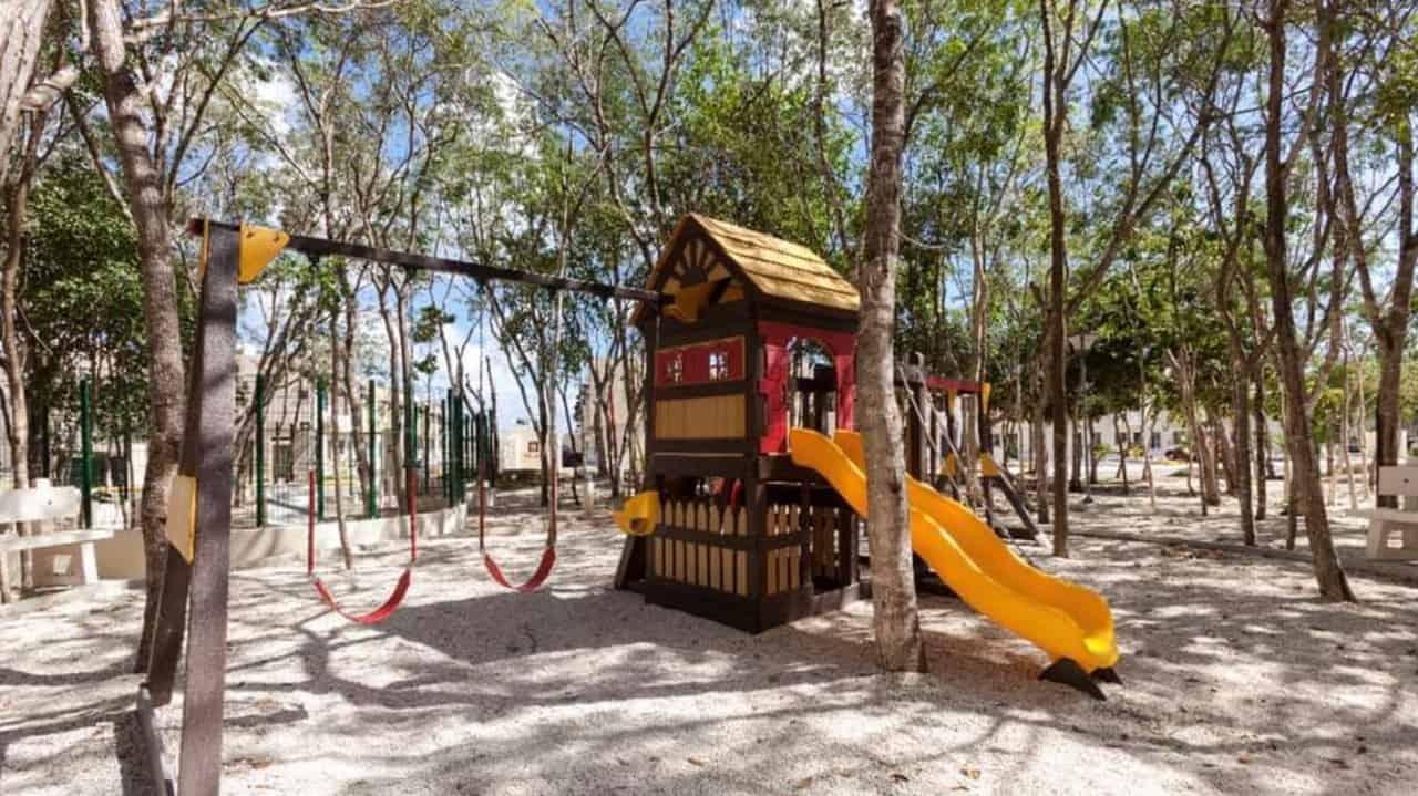 Kids playground with swings and mini house slide in the park at Real Amalfi