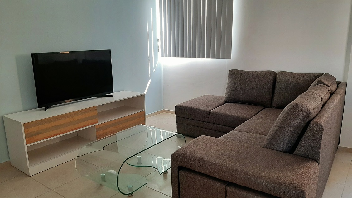 Living room with a sofa in front of tv screen at Punta Estrella