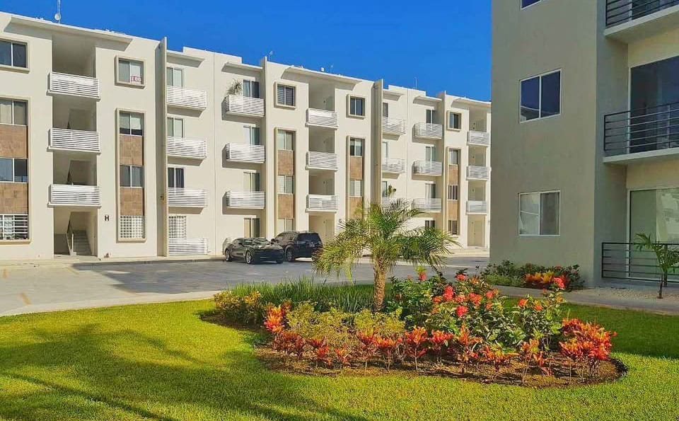 A building with a lawn and flowers in Paseo los Olivos Playa del Carmen