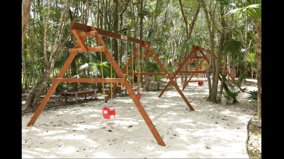 Kids playground with two swings in the park at Senderos Mayakoba