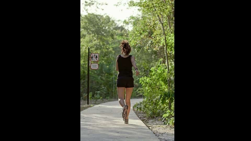 Park and a woman jogging on the running track at Senderos Mayakoba