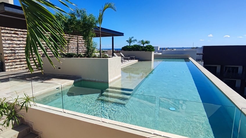 Rooftop pool with stairs leading to the water and pergola at Syrena Studio Living