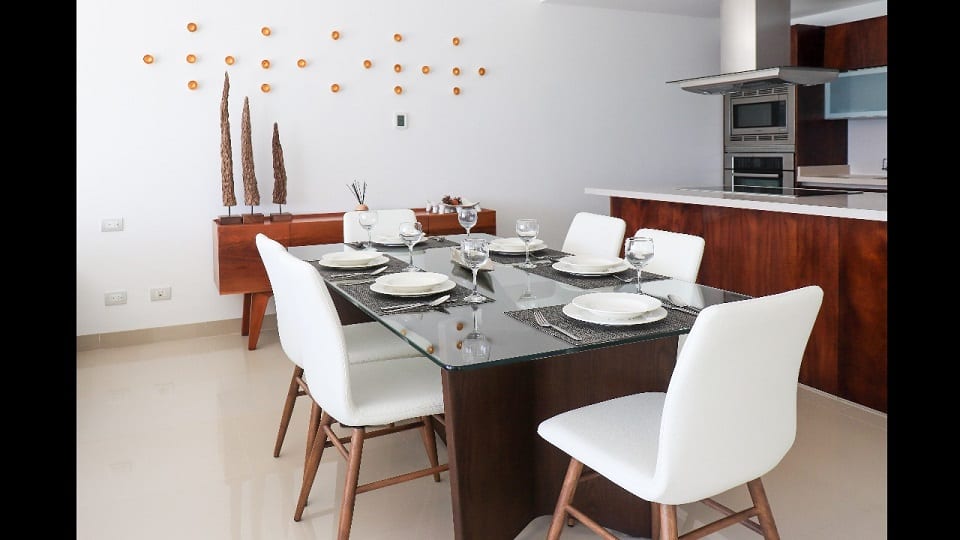 Dining table in front of the kitchen with campana over the stove at Mareazul Beachfront Residences