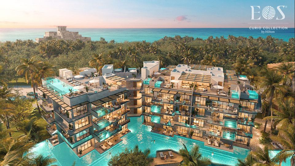 View of illuminated residential towers with pool complex and ocean view at Eos Tulum