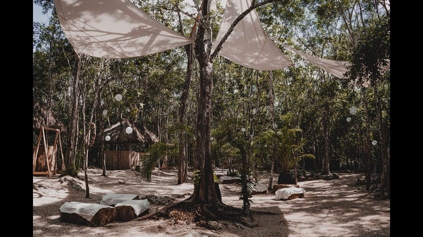 Common area with rustic outdoor decor with hay bundles covered by white sheets and white lamps in the jungle at Kuyabeh Tulum