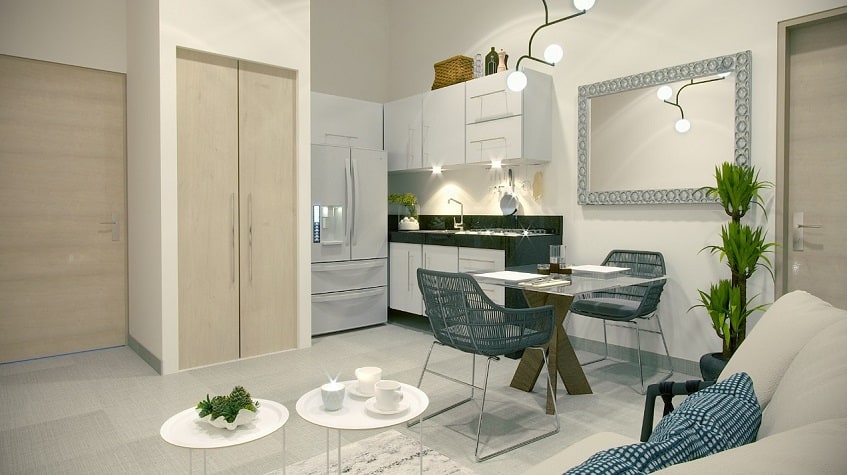 White kitchenette with black marble in front of small dining table and sofa in Musa del Carmen