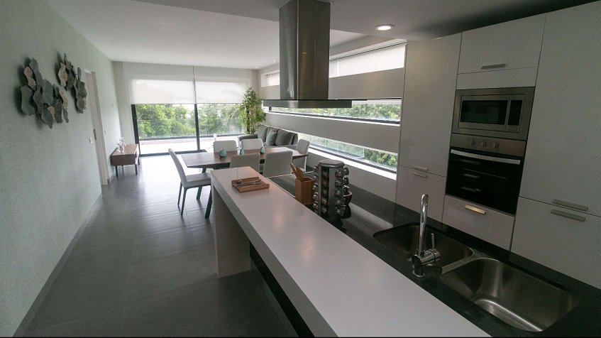 White kitchen with island sink and campana over a stove at Nick Price Residences
