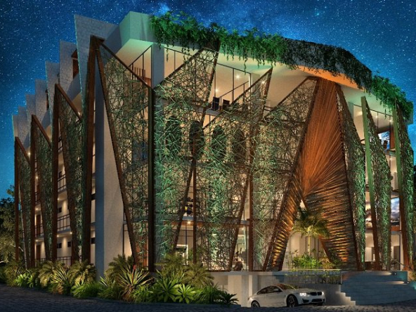 Illuminated building facade with a car leaving from underground parking at Akua Tulum
