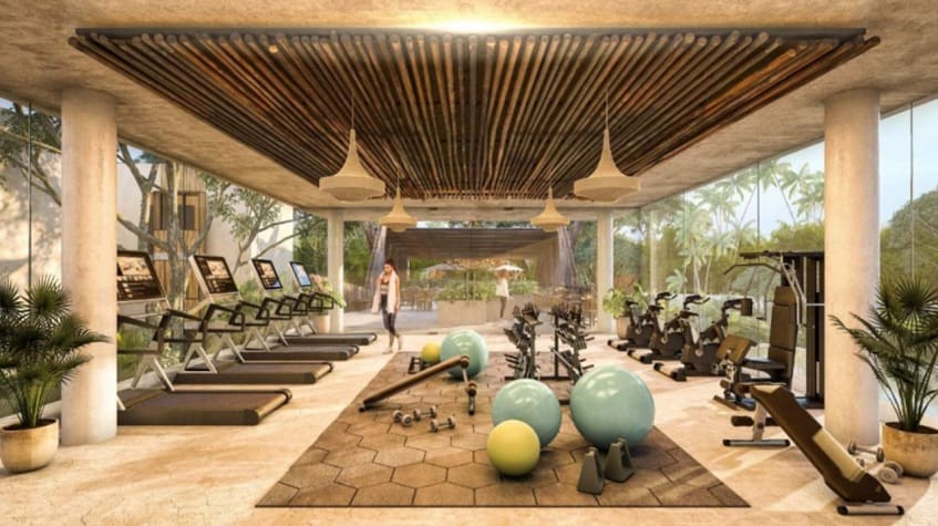 Indoor large gym with glass walls at and view of jungle Ophelia Tulum