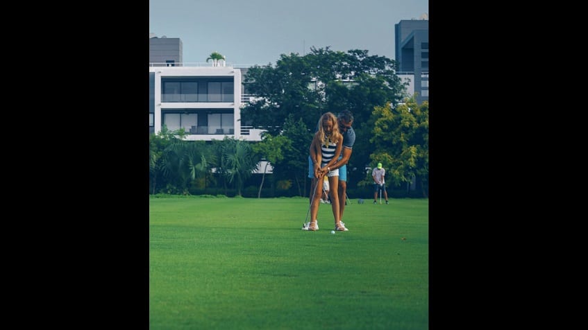 Golf course in front of residential building and a couple playing at Nick Price Residences