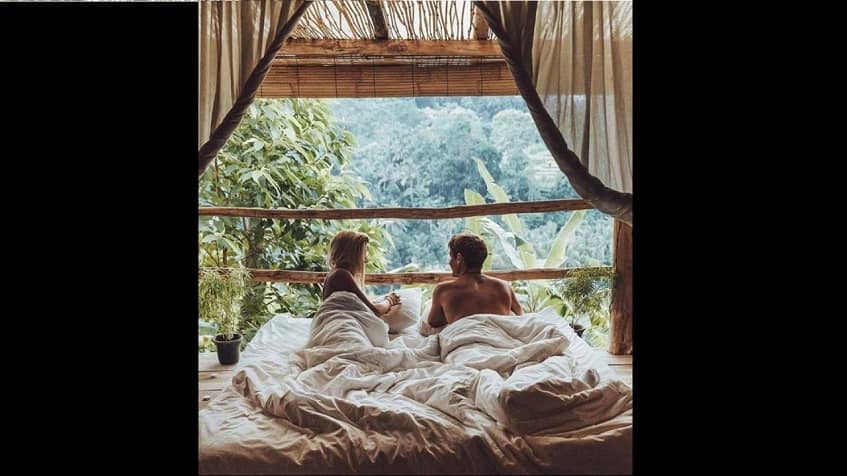 Bedroom with couple in the bed in front of no window balcony with jungle view at Kuyabeh Tulum