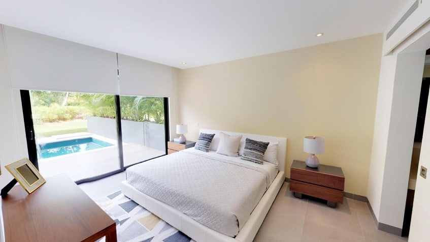 Bedroom with a bed next to large window with a pool view at Nick Price Residences