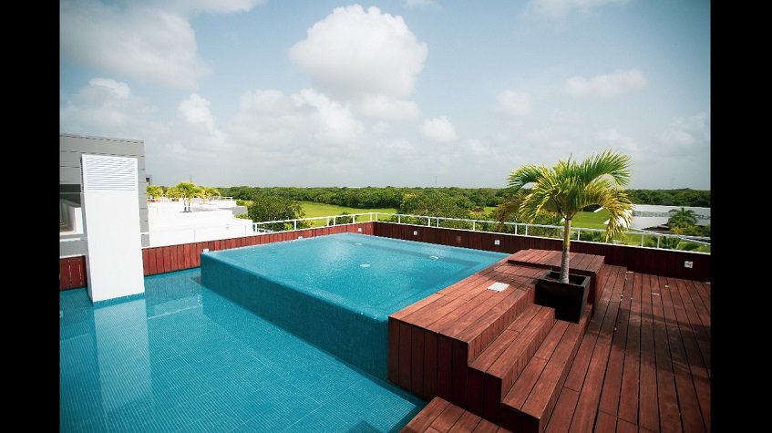Rooftop swimming pool surrounded by wooden deck at Nick Price Residences