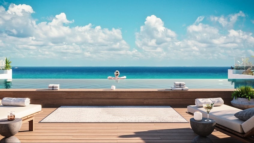 Rooftop pool with a woman inside watching the ocean at Vibbe Luxury Condos