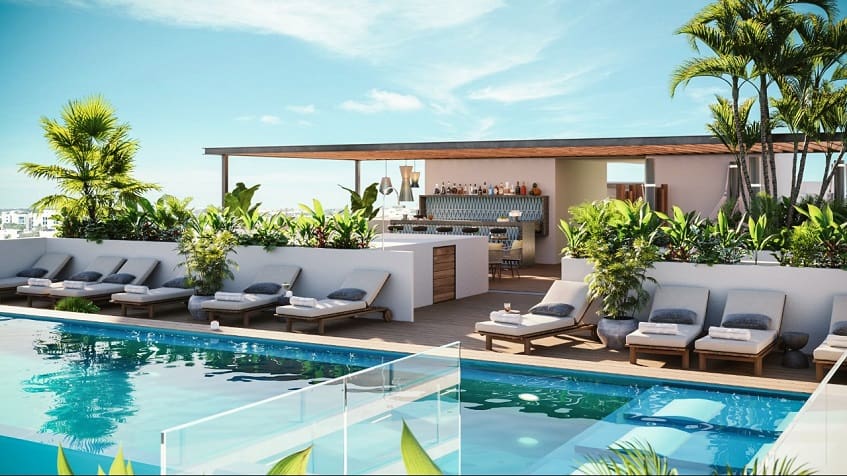 Rooftop pool and bar surrounded by vegetation at Vibbe Luxury Condos