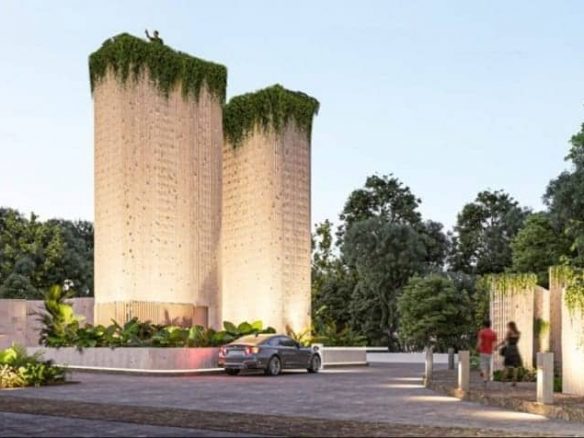 Car passing by the two towers and the rooftop covered with plants at Dharma Tulum