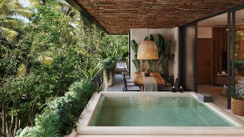Terrace with a small pool next to the large table surrounded by vegetation at Talulah Tulum