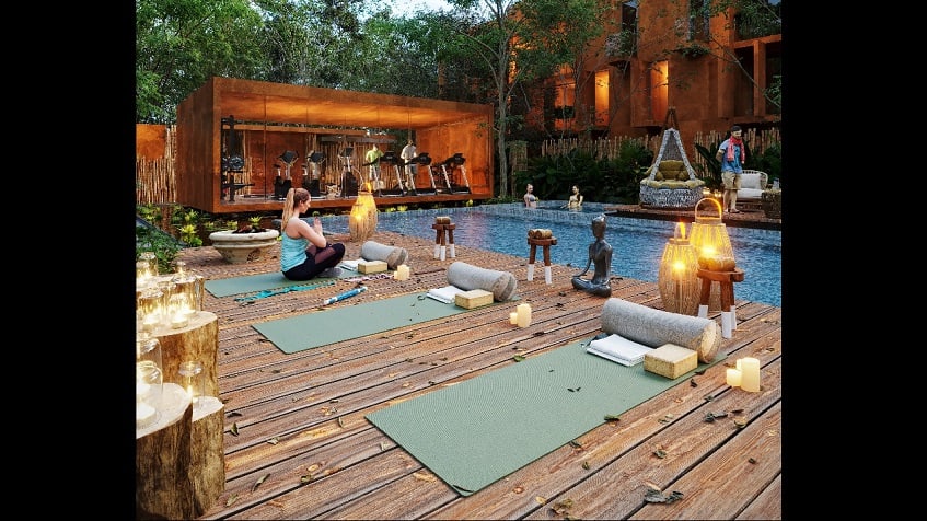 Yoga deck and woman meditating next to the pool, two women swimming at Kune Tulum
