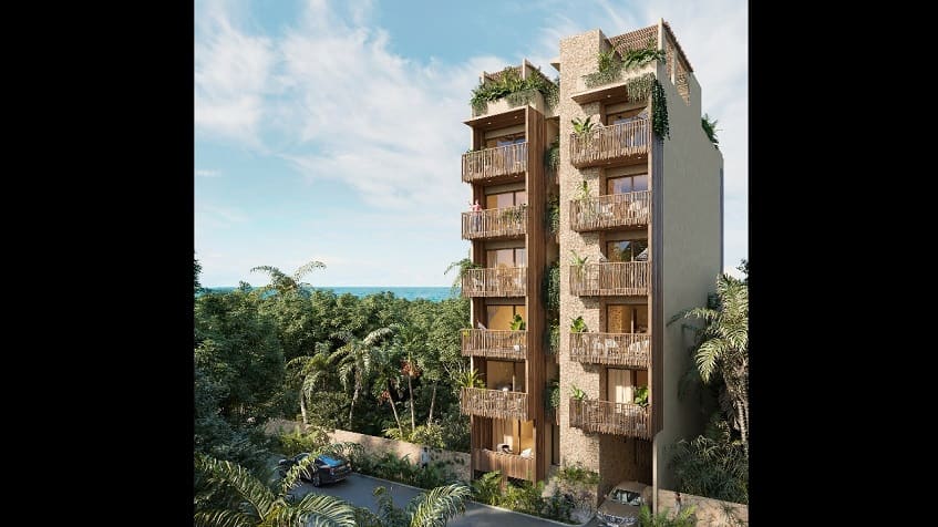 Tall residential building facade in the jungle, ocean in the background at Caribique Playa del Carmen