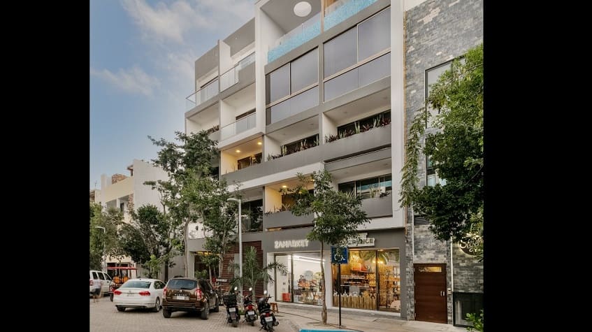 Residential building facade with shops on the ground floor, street parking at Gaia Residence