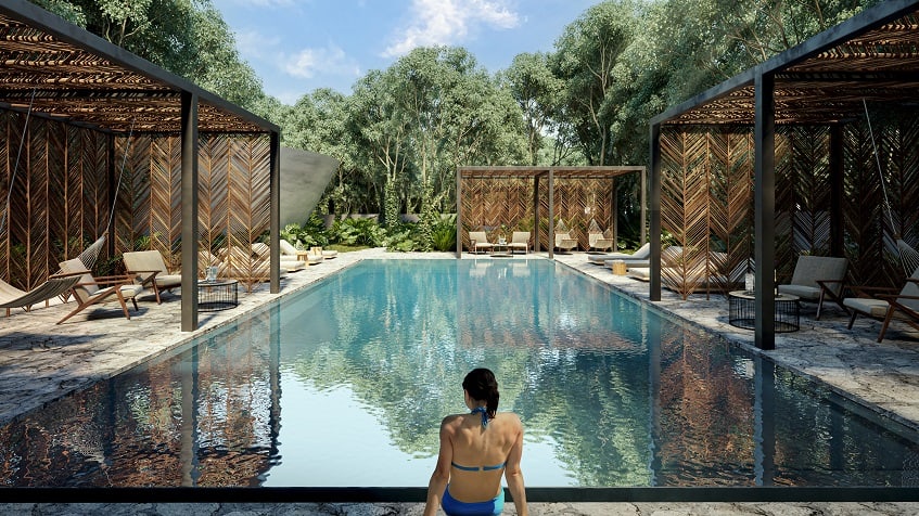 Swimming pool and a woman entering to the water, three pergolas with sunbeds and hammocks at Icht Tulum