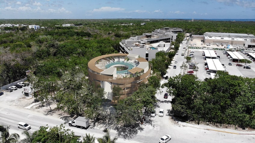 Round residential building next to a large commercial parking at Tuk Orien Tulum