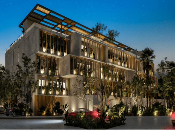 Illuminated residential building surrounded by vegetation, cars passing by at Carey Tulum Condos