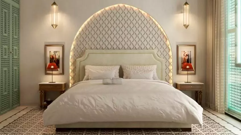 Bedroom with a large bed in the middle, light illumination over a headboard at Pink Riad Tulum