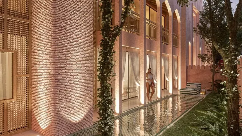 Residential building facade and a woman standing on a terrace by a pool at Pink Riad Tulum