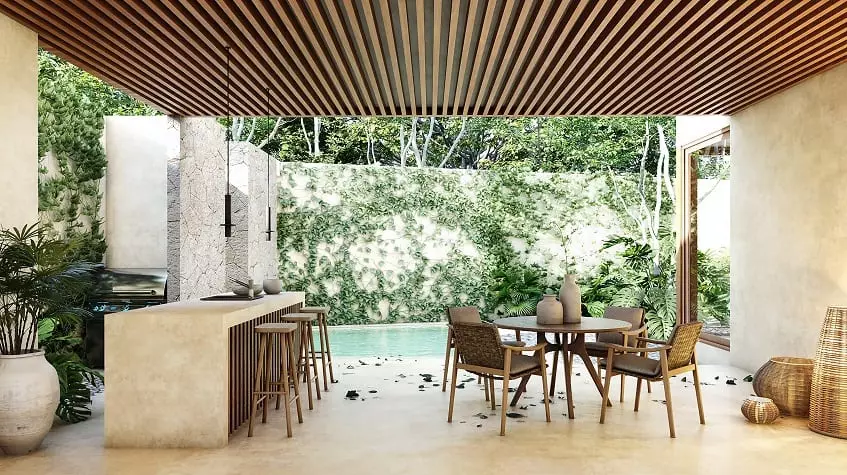 Pool terrace under pergola with kitchen island with stools and round dining table at Retiro Tulum Artisan Homes