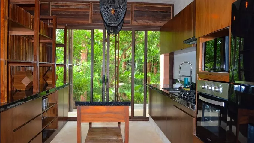 Kitchen with a kitchen bar, large sliding door opening to a garden at Kiino Cozumel