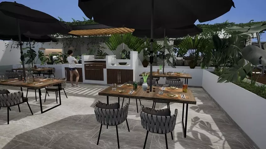 Rooftop dining area with a woman in front of a grill/kitchen at Ix Tulum Apartments