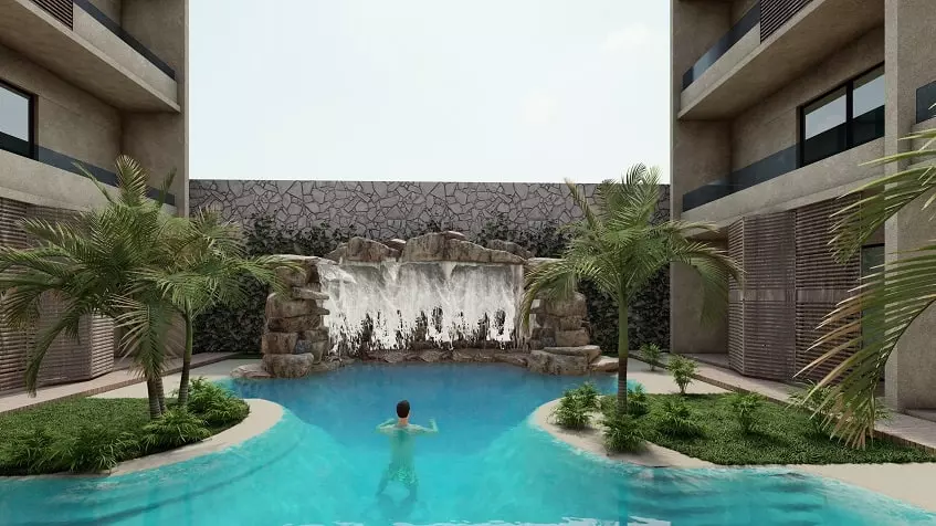 Pool and waterfall, man swimming, residential building facade at Cocay Lofts Tulum