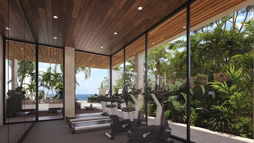 Gym room with tall windows with garden and ocean view at Nalu Puerto Morelos