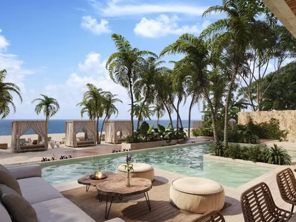Pool area next to the beach and beach beds and ocean, palm trees at Nalu Puerto Morelos