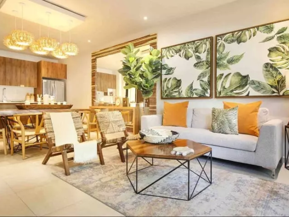 Living room with a dining table and kitchen, paintings with green leaves at Selvanova Playa del Carmen
