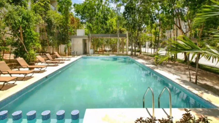 Swimming pool with a kids pool surrounded by green area at Selvanova Playa del Carmen