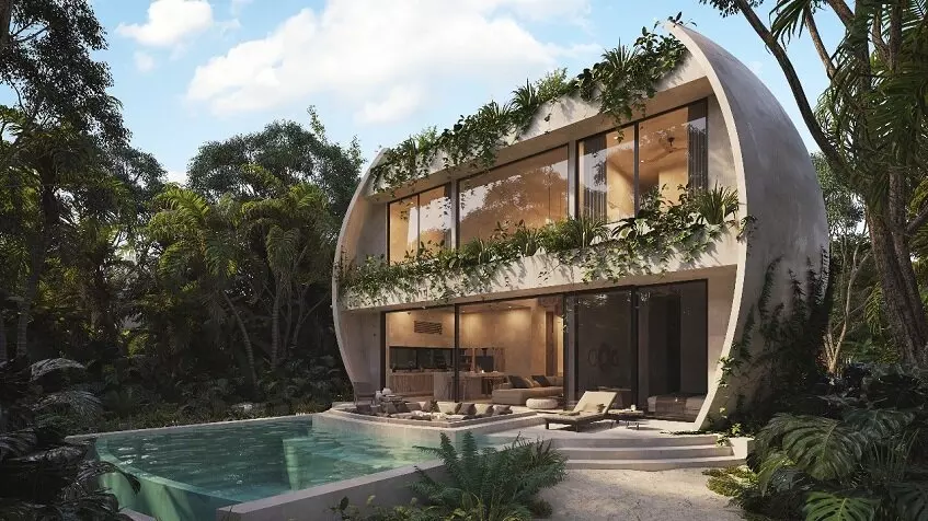 Facade of a two level round building with a pool surrounded by vegetation at Duna Tulum