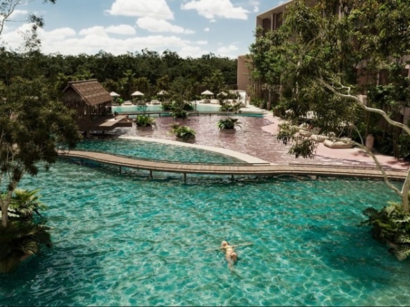 A view of the pool and a woman swimming in Wabi Tulum