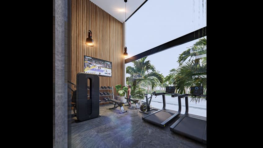 A gym with a woman standing watching TV in Hygge Tulum