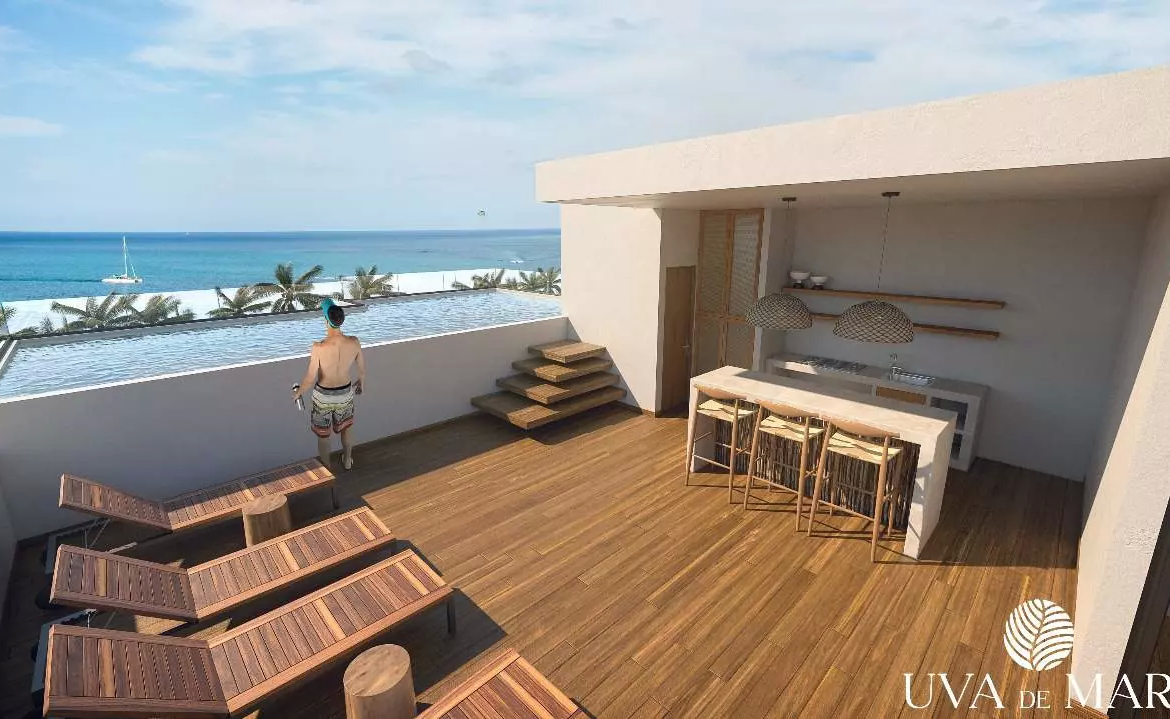 A terrace with pool, lounge chairs and a man looking out to sea at Uva del Mar Puerto Morelos