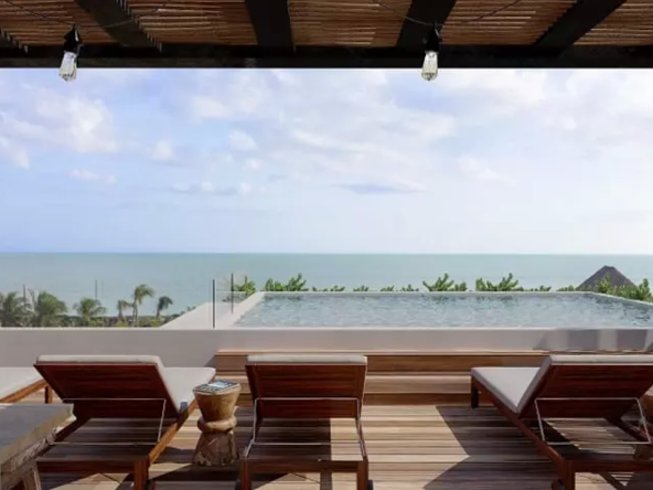 A solarium with lounge chairs and a pool overlooking the sea in Kaban Holbox