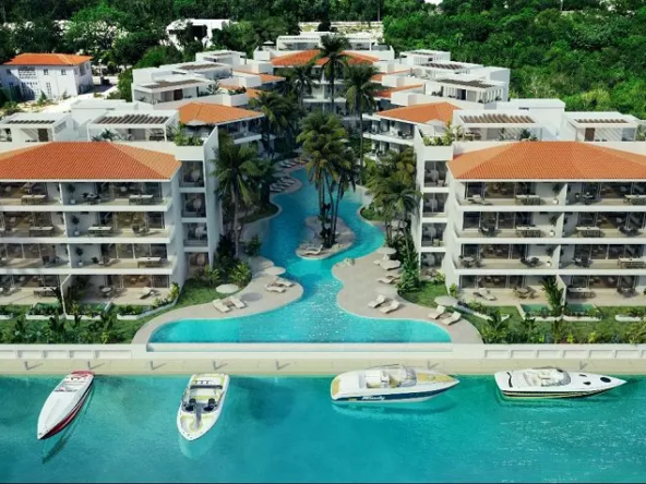 Ground floor pool in river shape between residential buildings with large terraces and boat pier at Puerto Aqua Puerto Aventuras