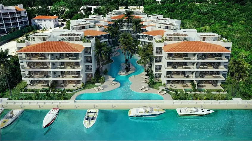 Ground floor pool in river shape between residential buildings with large terraces and boat pier at Puerto Aqua Puerto Aventuras