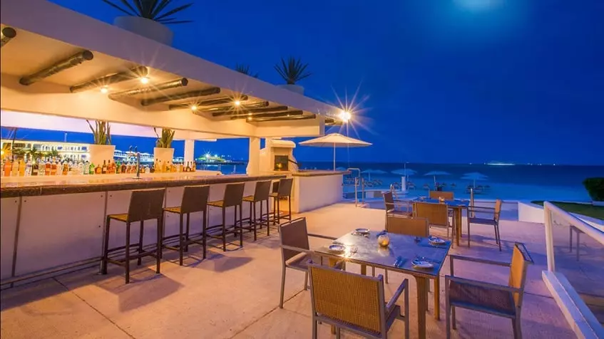 A beach bar with an ocean view at night at Vi-ha 36 Playacar