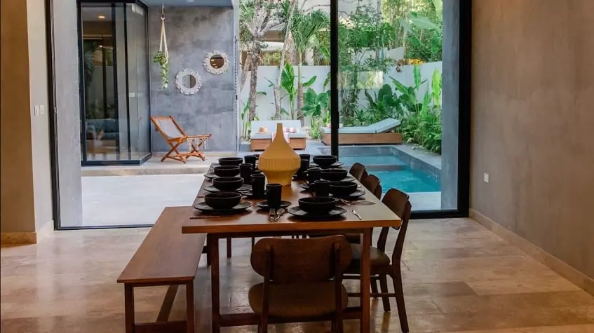 A large dining room with black plates and a view of the pool at Villa Alquimia Tulum
