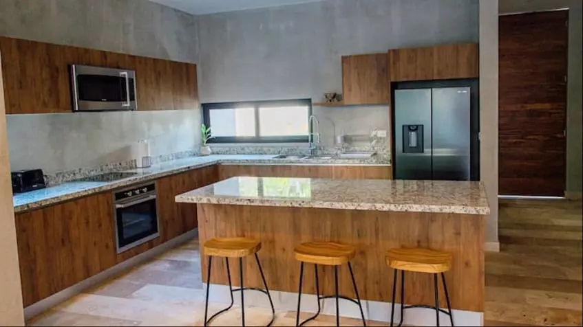 A full kitchen with stove, full-size refrigerator, and breakfast bar at Villa Alquimia Tulum