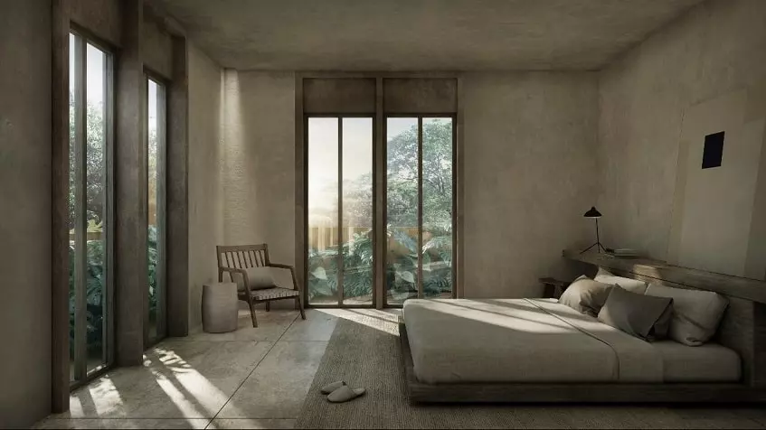 Master bedroom with an armchair in the corner and windows overlooking the garden in Candela Tulum