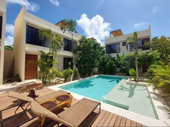 A pool, 2 houses, green areas and 2 lounge chairs in Poc ta Poc