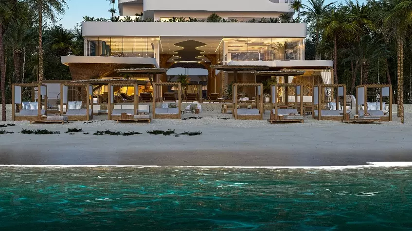 Facade of a beach club with beds and an ocean in front at Mara Bella Cancun